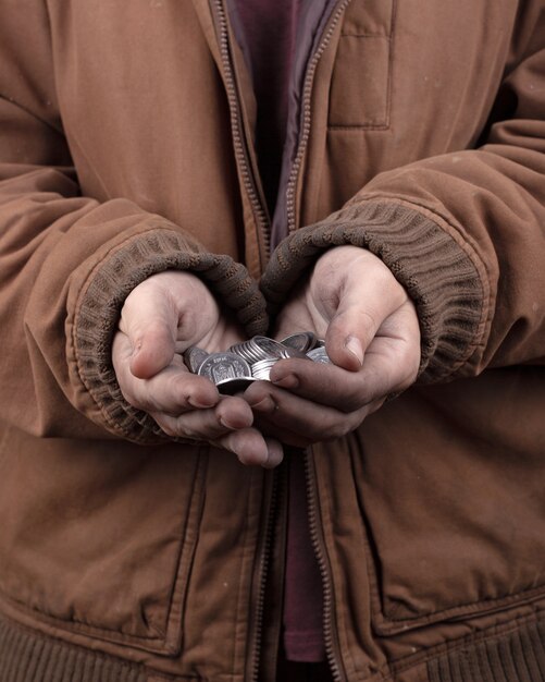 Beggar concept. outstretched hands of a homeless person asking for help. silver coins in the palms closeup