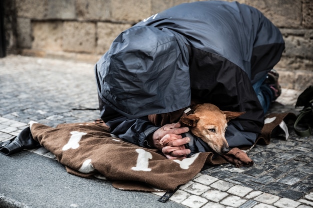 Mendicante con il cane che chiede l'elemosina, città europea