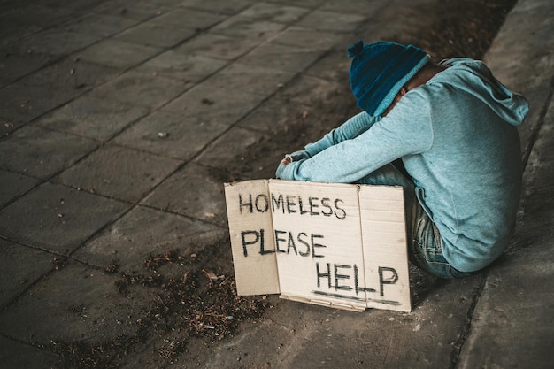 The beggars sit under the bridge with a homeless message Please help