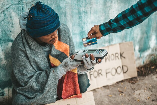 Photo beggars sitting under the overpass with a credit card and credit card swipe machine