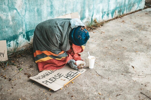 Foto mendicanti seduti per strada con messaggi per senzatetto, vi prego di aiutare.