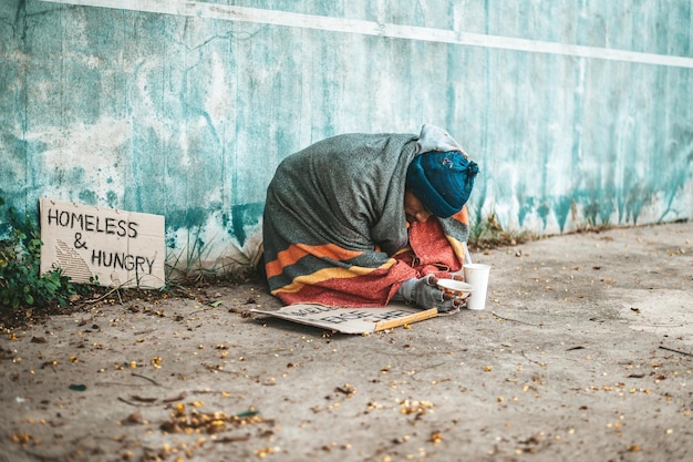 beggars sitting on the street with homeless messages please help