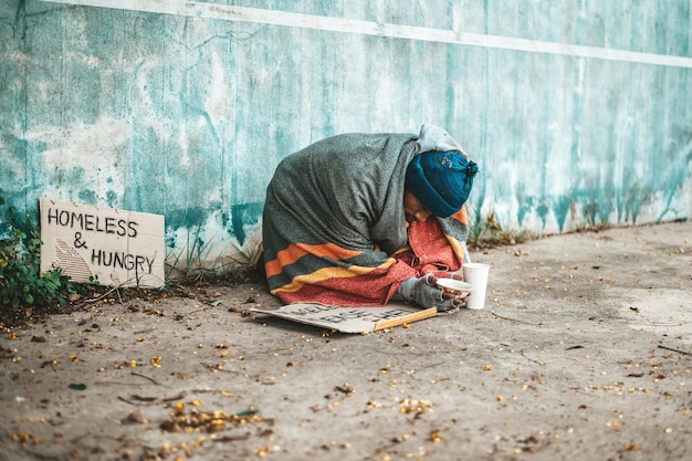 Foto mendicanti seduti per strada con messaggi per senzatetto, vi prego di aiutare.