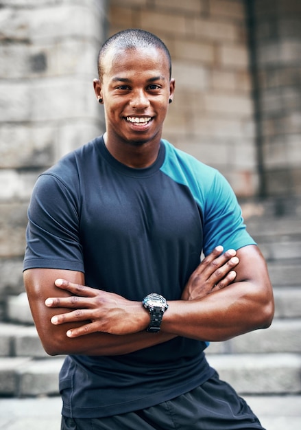 Begin de dag altijd met een glimlach en een training Portret van een knappe jonge sportman die poseert met zijn armen buiten gevouwen