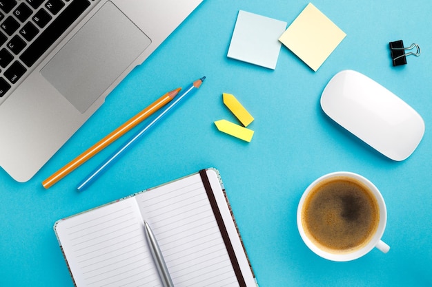 Begin van de ochtend werk bureau met een kopje koffie computer laptop notebook pen blauwe textuur tafel Bedrijfsconcept achtergrond