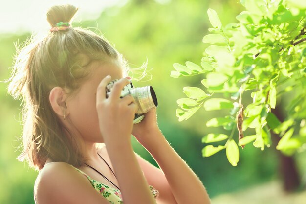 Beginfotograaf. Een klein meisje neemt foto's van een boom op haar filmcamera