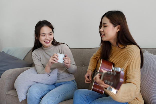 Una donna principiante con la migliore amica che suona una lezione di chitarra acustica