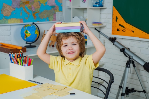 Beginning of lessons Cute child boy in classroom near blackboard desk Chalkboard copy space Happy cute clever boy with book