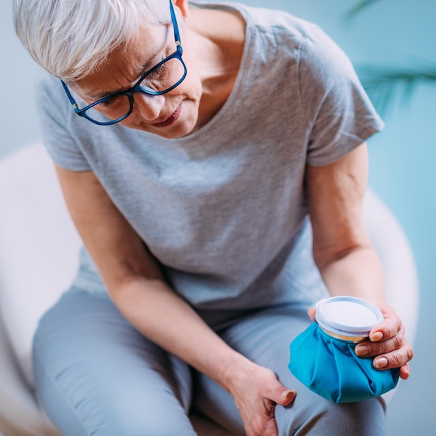 Behandeling van kniepijn Senior Woman Holding Ice Bag Pack op haar pijnlijke knie