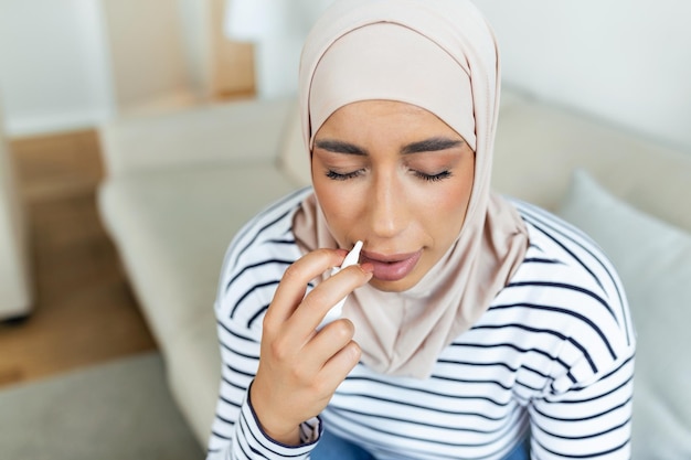 Behandeling voor allergieën of verkoudheid Arabische moslimvrouw die neusspray gebruikt Druppels medicijnen in haar neus Rhinitis Allergie