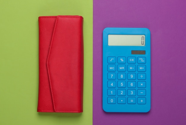 Beheer het gezinsbudget. Boodschappen kosten. Blauwe rekenmachine met rode lederen portemonnee op paars groen oppervlak. Bovenaanzicht