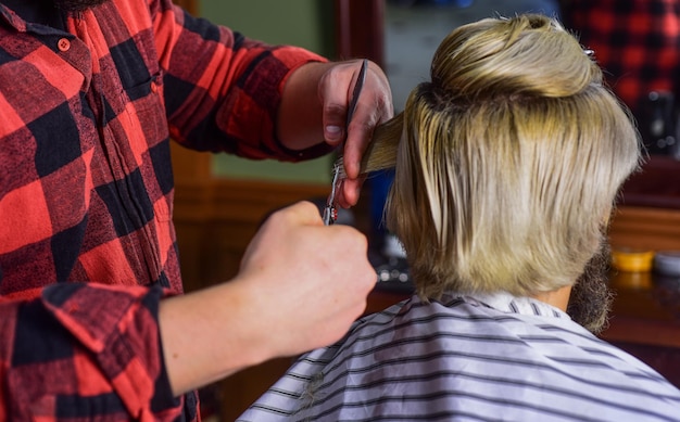 Beheer uw verwachtingen Man met lang geverfd blond haar close-up achteraanzicht Haar knippen Kapper maken kapsel voor bebaarde man kapperszaak achtergrond Hipster cliënt kapsel krijgen Kapper schaar