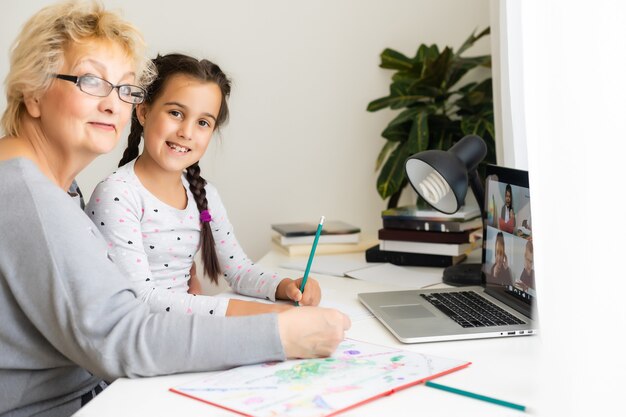 Behulpzame oma. Behulpzame liefhebbende oma die haar schattige kleindochter helpt bij het maken van huiswerk