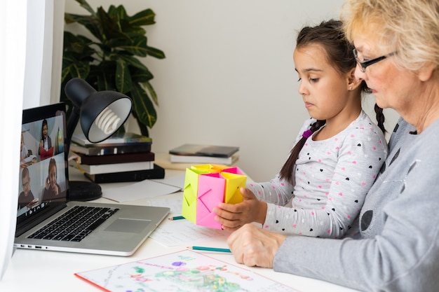 Behulpzame oma. behulpzame liefhebbende oma die haar schattige kleindochter helpt bij het maken van huiswerk