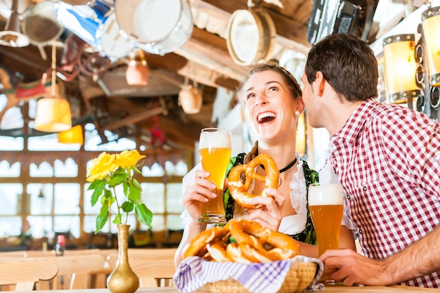 Beierse paar klederdracht dragen, flirten en bier drinken in restaurant