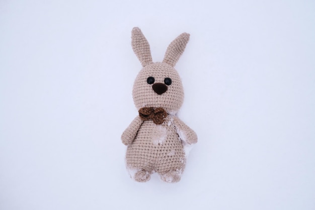 Beige amigurumi rabbit with long ears and brown nose and bow\
tie