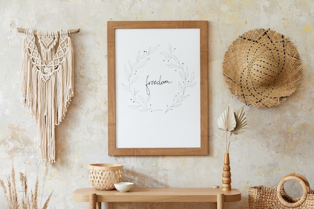 Photo beige boho interior of living room with mock up poster frame, elegant accessories, dried flowers in vase, wooden console and hanging macrame in stylish home decor.