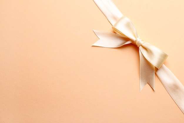 Photo beige bow and ribbon on a pink background