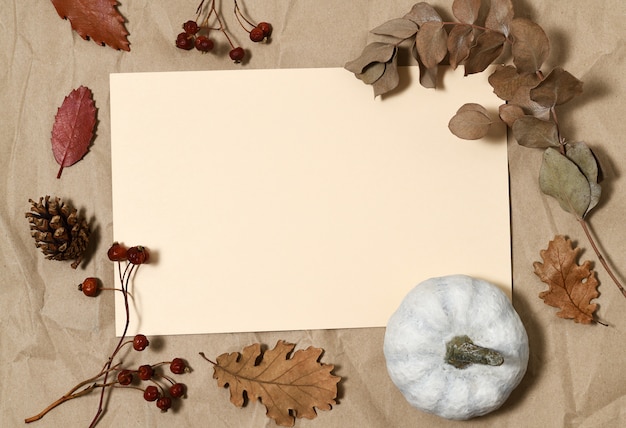 Beige card with white pumpkin, autumnal leaves and berries