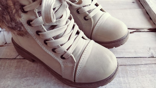 Beige children's boots with laces Beautiful fashionable leather or suede shoes in a light shade on a wooden background Exhibition of shoes Shoes on display or shelf Sale of shoes