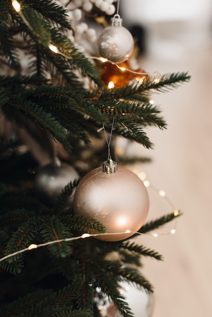 Beige Christmas ball on a Christmas tree in a light interior 