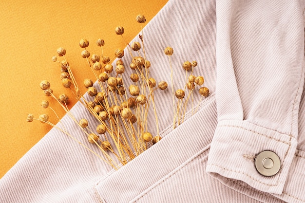 Beige denim overhemd en linnen bloemen close-up, plat gelegd, om te bekijken. Natuurlijk duurzaam linnen stoffen concept. Comfortabele casual kleding achtergrond. Stoffen gemaakt van gerecyclede materialen.
