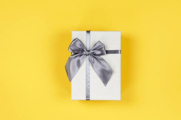 Beige gift box on yellow background top view