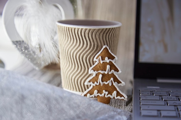 Beige kartonnen beker met warme drank en koekje in de vorm van een kerstboom