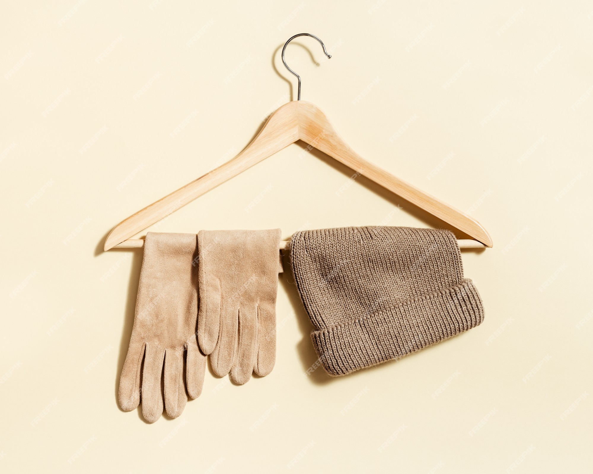 Premium Photo  Beige knitted hat and suede gloves on clothes hanger with  beige color background