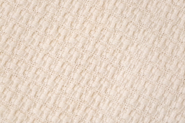 Beige knitted throw fabric texture background Closeup