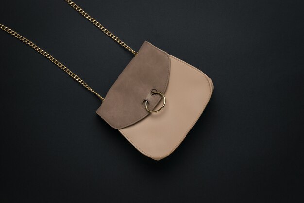 Photo beige leather women's bag with a chain strap on a black surface