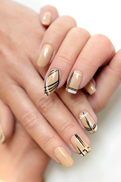 Manicure beige con linee nere su diverse forme di unghie