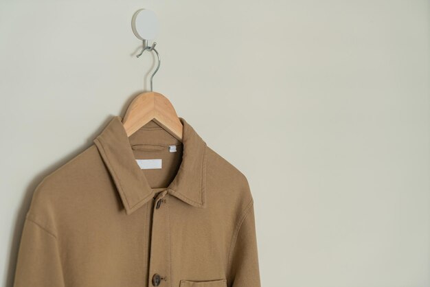 beige pak hangend met houten hanger aan de muur