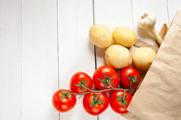 Beige paper bag on a wooden white, vegetables from the store