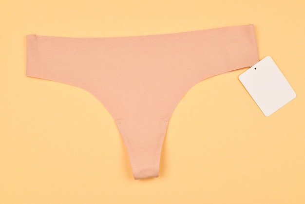 Beige seamless panties with tag on beige background. space for text or design