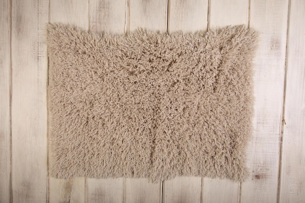 A beige sheepskin cushion on a wooden surface.