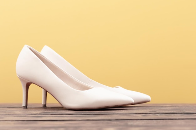 Beige shoes on wooden floor on yellow background