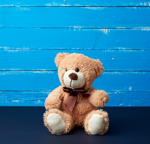 Beige teddy bear sitting on a blue wooden surface