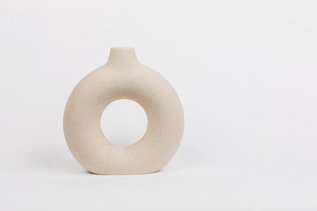 Beige vase of a beautiful flat round shape on a plain white background The concept of Minimalism