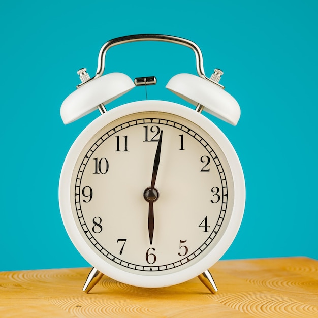 Beige vintage alarm clock on a blue background.