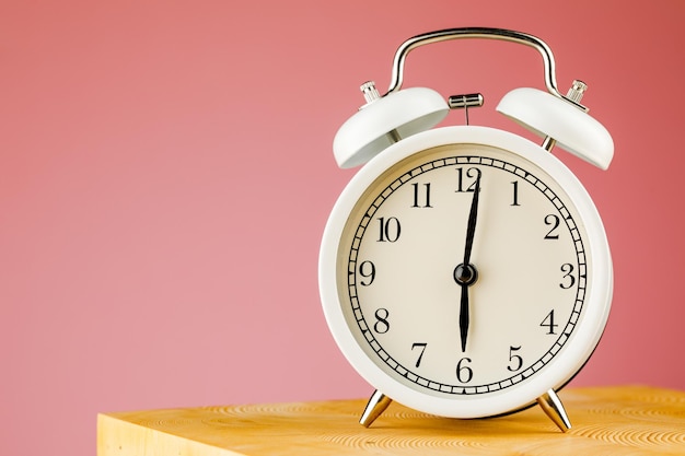 Beige vintage alarm clock on pink background