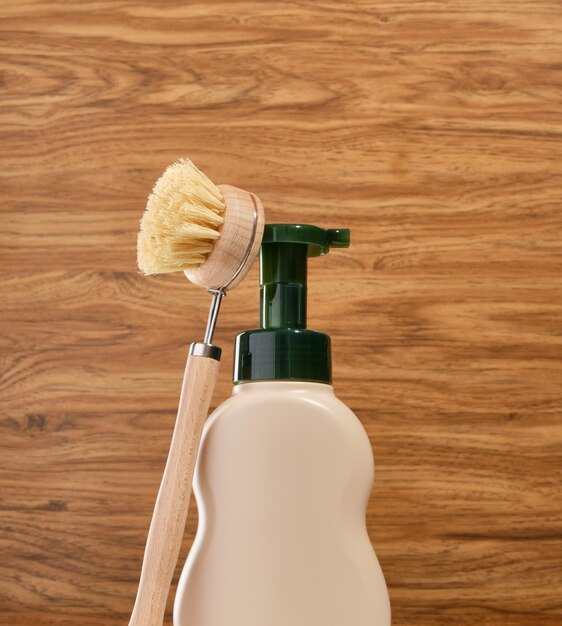 Foto beige wasmiddeldispenser en natuurlijke milieuvriendelijke afwasborstel op een houten achtergrond