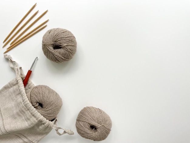 Beige wollen strikken van garen breien naalden en een haak voor het breien vielen uit een handgemaakte tas