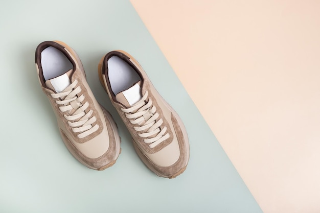 Beige women's leather sneakers top view on a greenbeige background Spring or autumn casual shoes