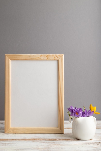 Beige wooden frame mockup with snowdrop crocus flowers on gray
paper background still life copy space