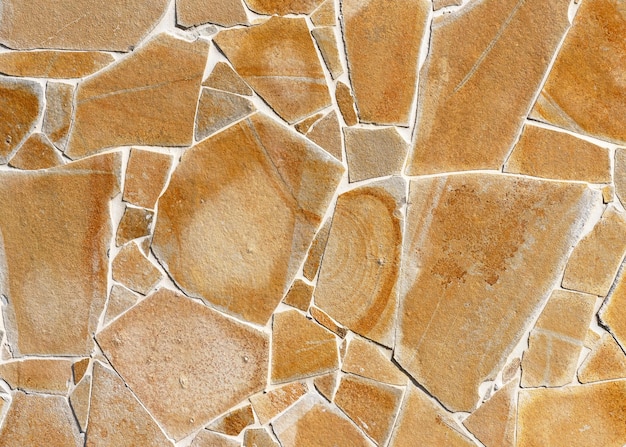 Beige and yellow rustic mosaic nature stone wall from small parts Vintage decorative elements