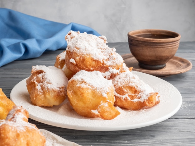 コーヒーと木製のテーブルに粉砂糖を振りかけたBeignet。