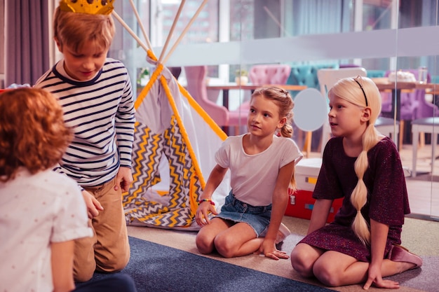 Being in all ears. Cheerful kids spending time in playing center, having birthday party