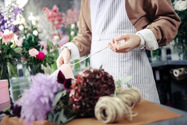 Being ready. Professional florist wearing uniform while working in floral studio