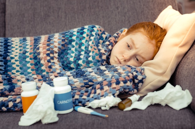 Photo being sick. cute gloomy girl being surrounded by medicine while being sick